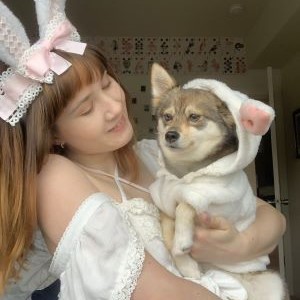 Megan in white and pink bunny ears and her small dog kiwi in a white bunny costume